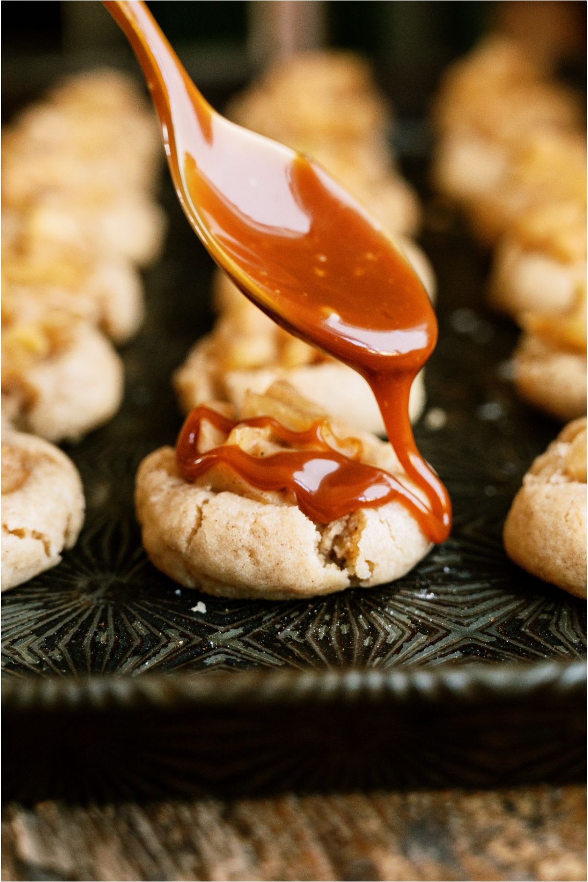 A spoon drizzling caramel sauce on top of a Apple Pie Cookie.