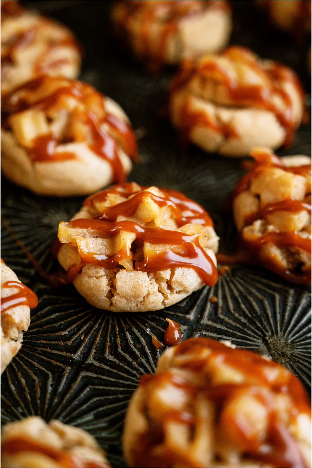 Apple Pie Cookies drizzled with caramel on a baking sheet.