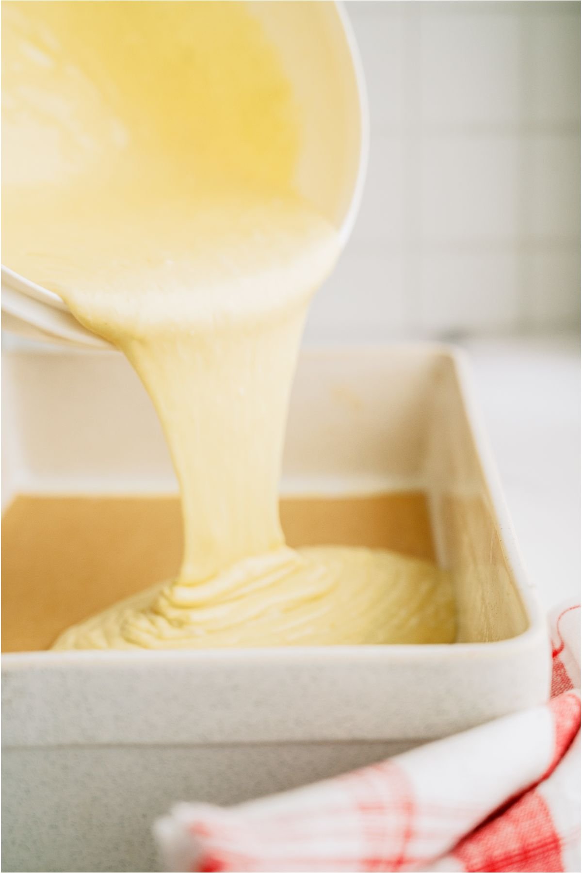 Cake Mix batter being poured from a mixing bowl into a 9x13 pan.