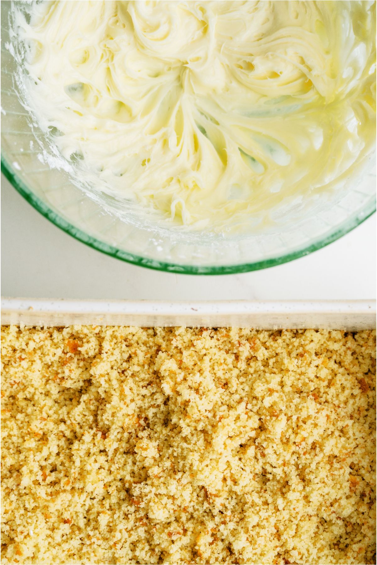 Frosting in a mixing bowl and a crumbled up cake in a cake pan.