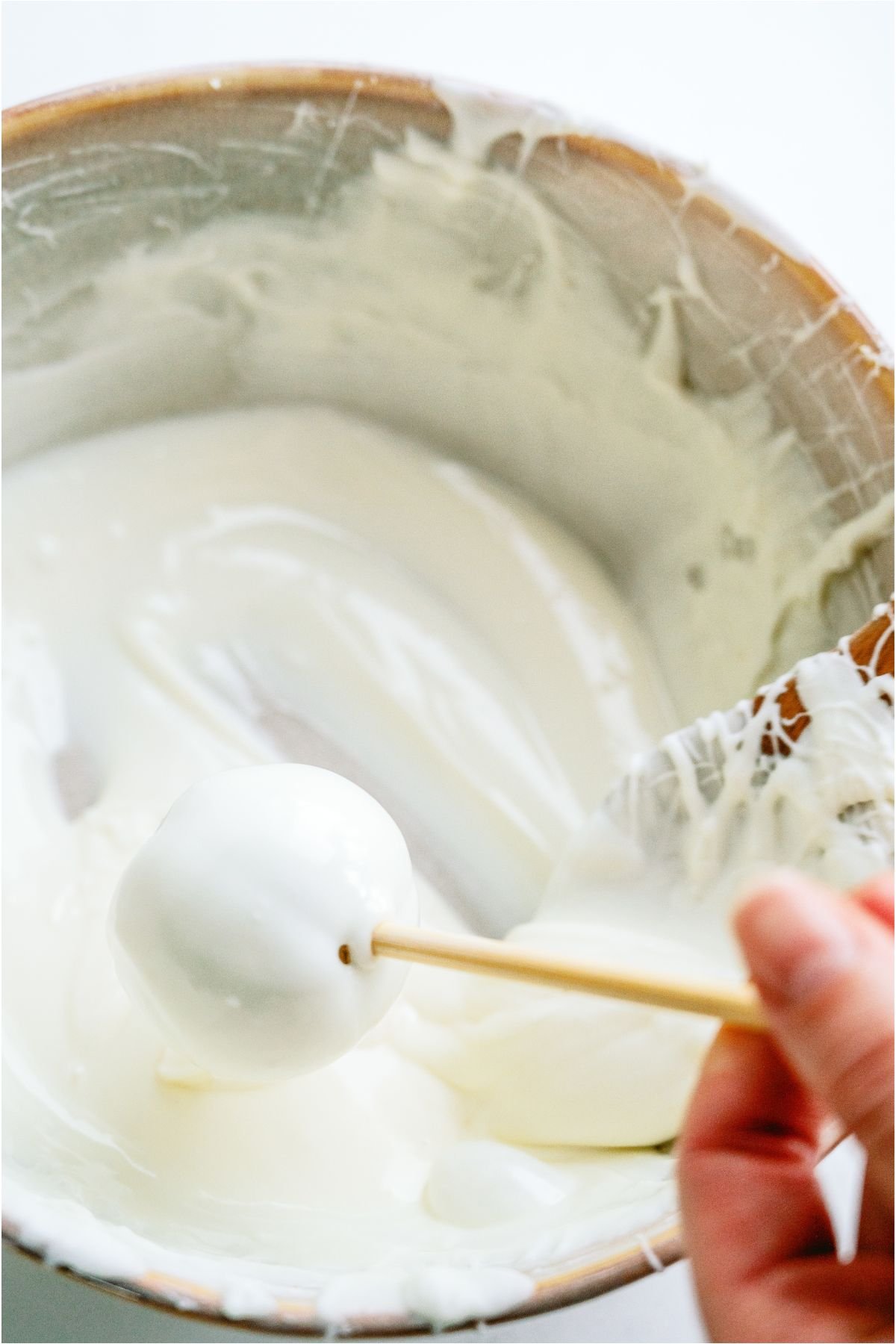 Dipping each cake ball into a bowl of melted white chocolate.