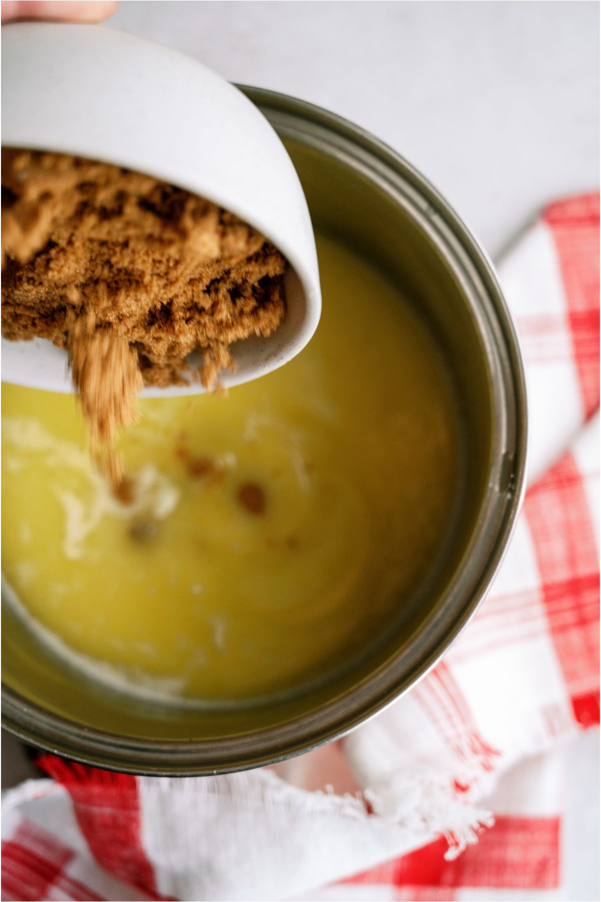 Sugar being poured int o a saucepan with melted butter