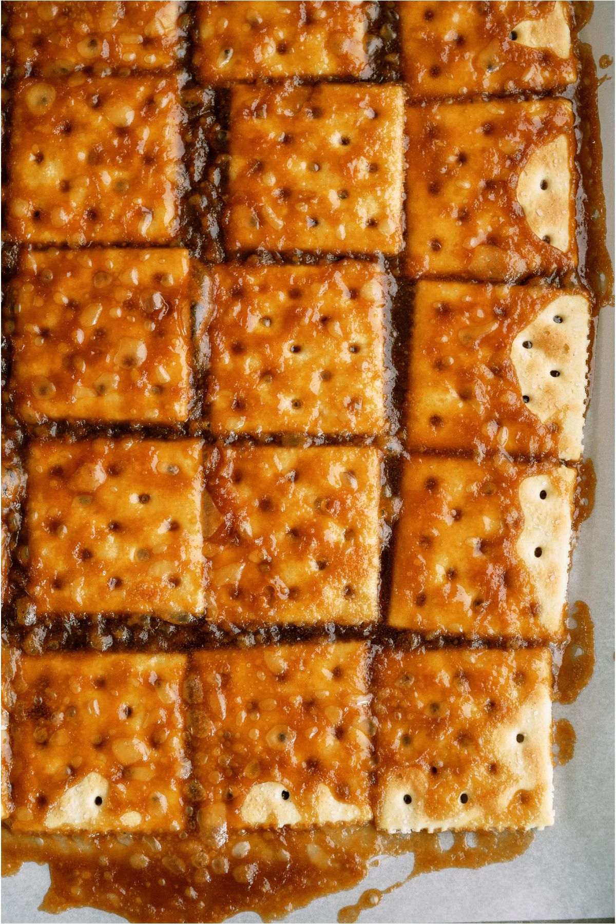 Saltine crackers laid out on a baking sheet with homemade caramel spread all over.