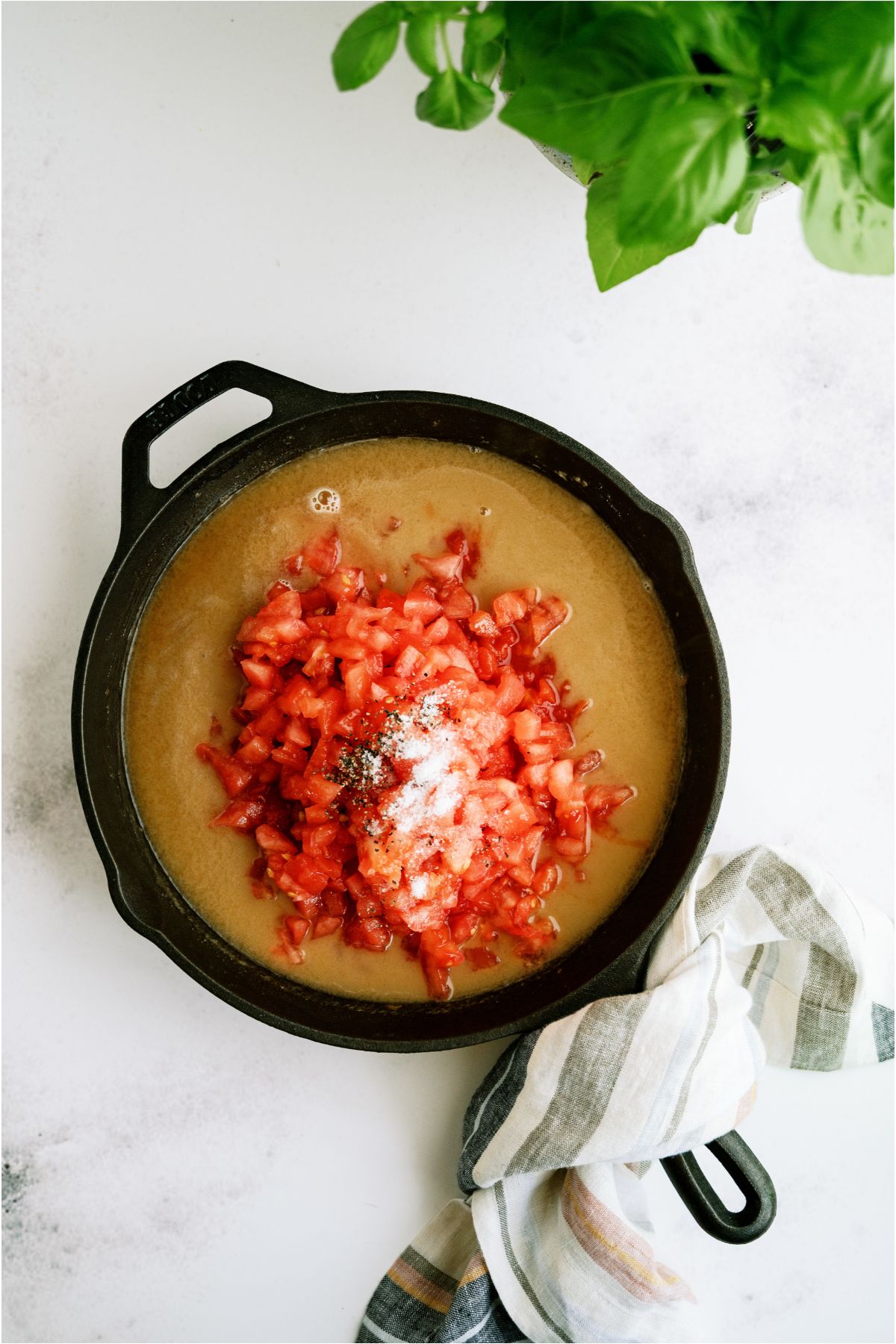 Large skillet with broth diced tomatoes and seasonings dumped on top.