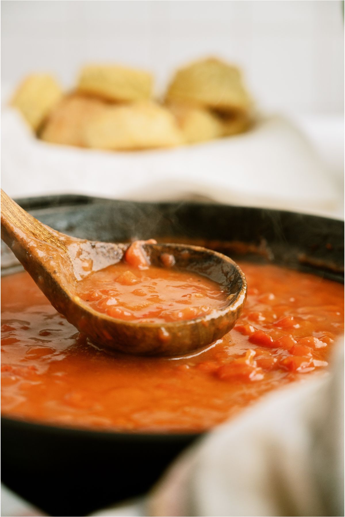 A large skillet with Tomato Gravy (Traditional Southern Recipe) and a wooden spoon lifting some out of the pan.