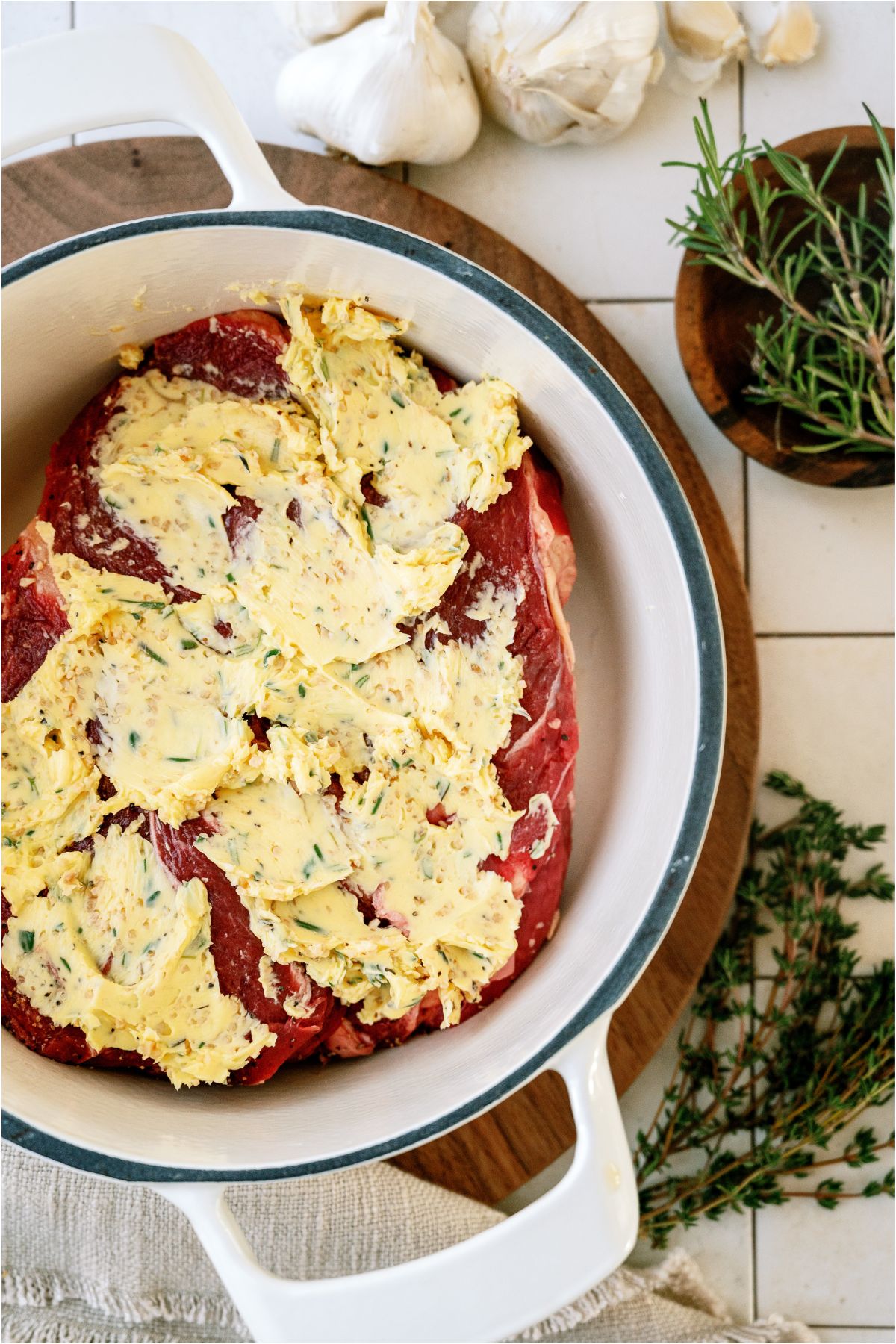 A roast in a large roasting pot covered with garlic butter.