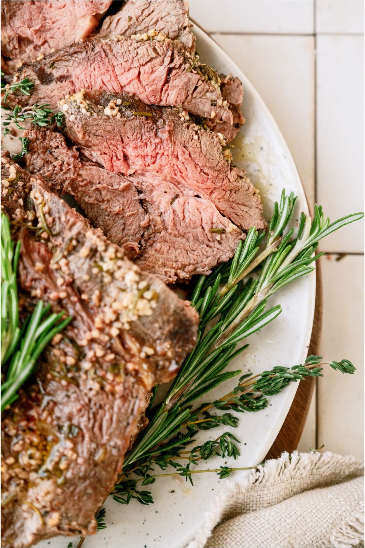 Top view of Garlic Butter Beef Roast on a serving plate. Some of the roast is sliced.