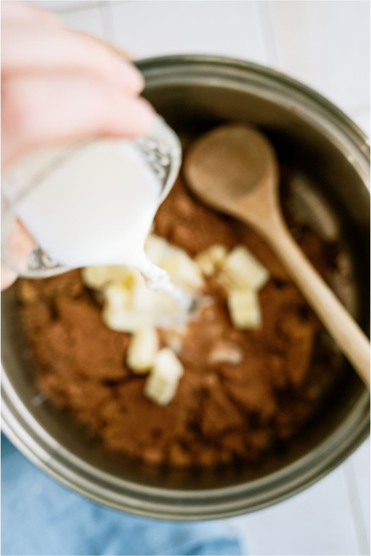 Adding milk to ingredients in a saucepan.