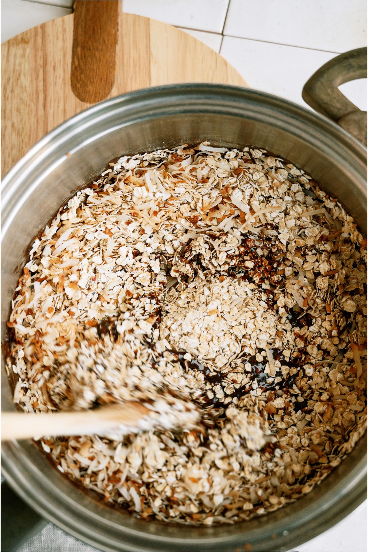 Stirring oats into saucepan with. a wooden spoon.