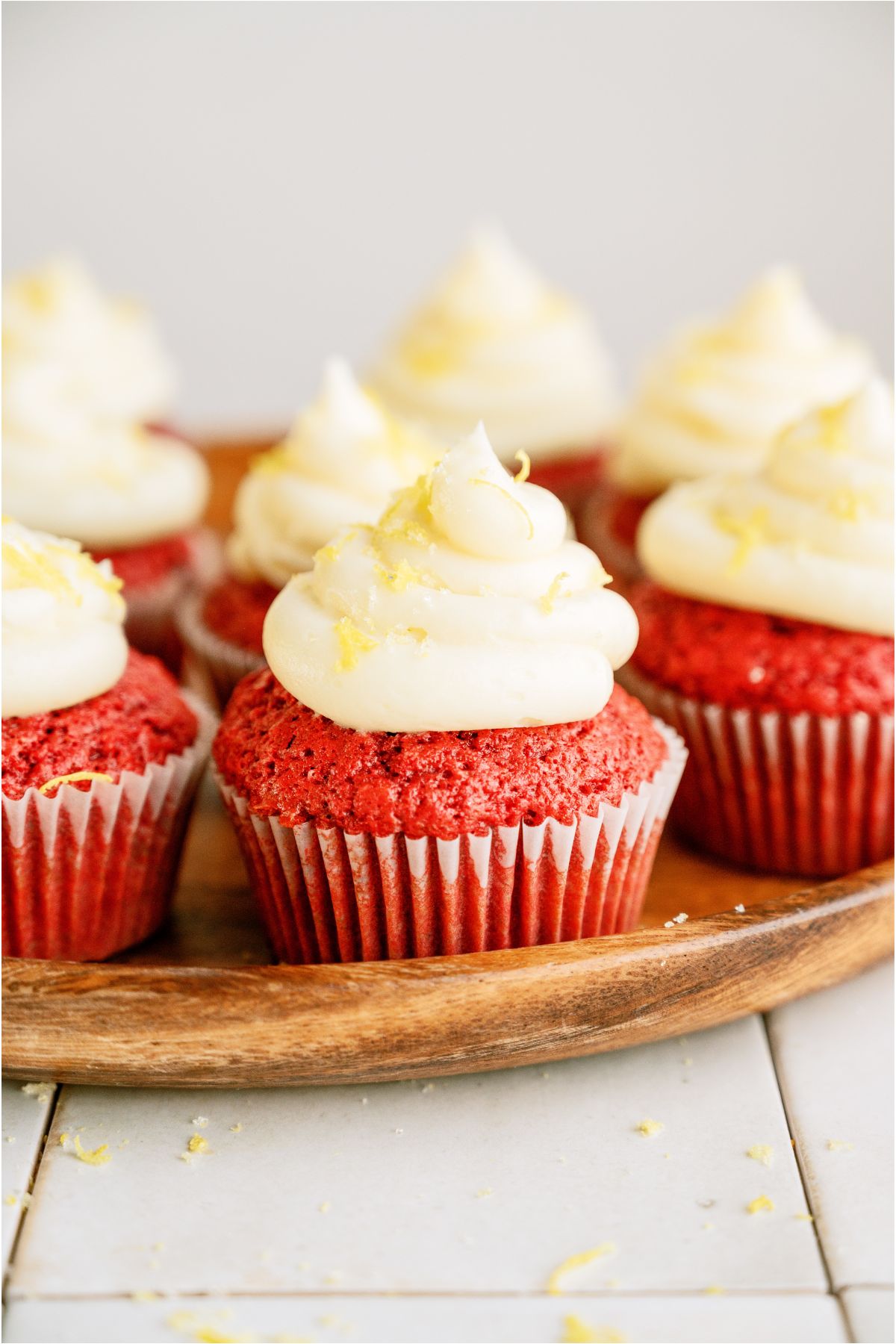 Frosted Red Velvet Cupcakes on a wooden serving platter.