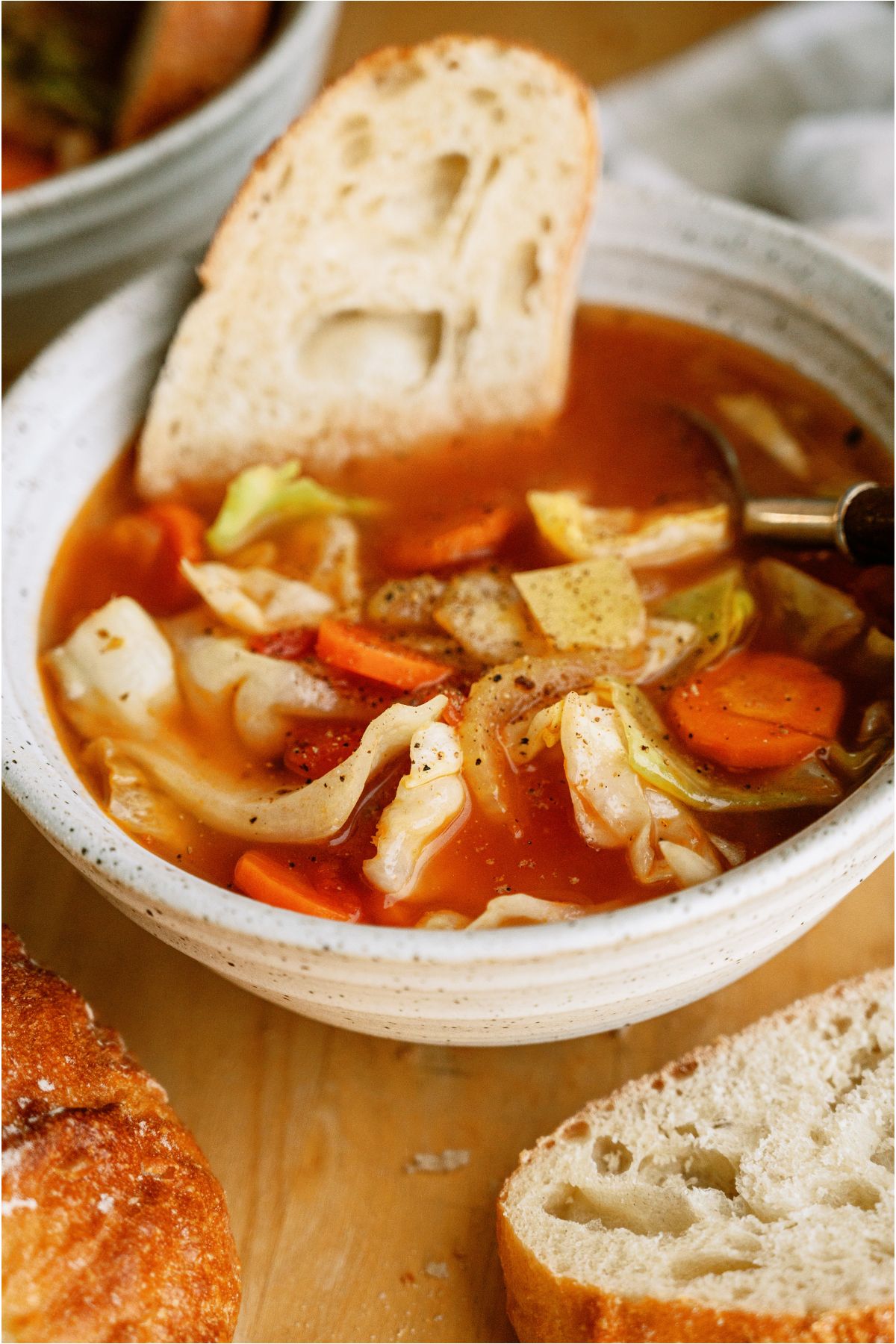 A bowl of Cabbage Soup with a slice of crusty bread in it.