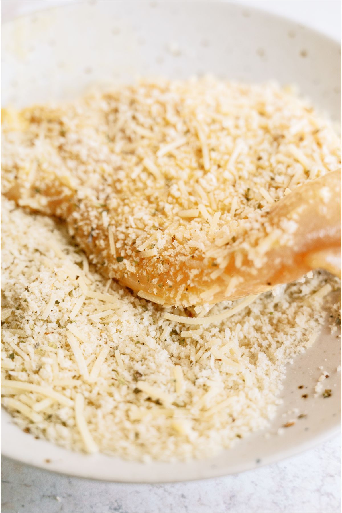 Covering dipped chicken breast in panko crumbs.