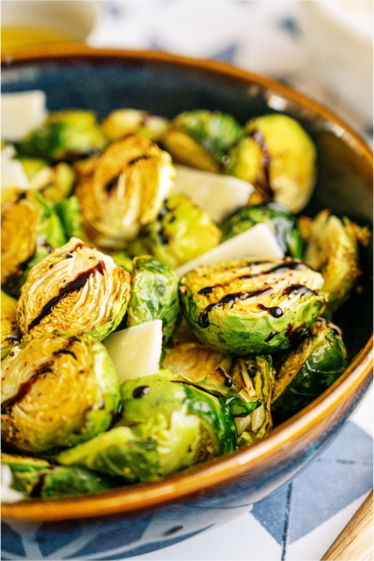 Side view of Crispy Air Fryer Brussel Sprouts in a serving bowl with balsamic glaze on top of them.