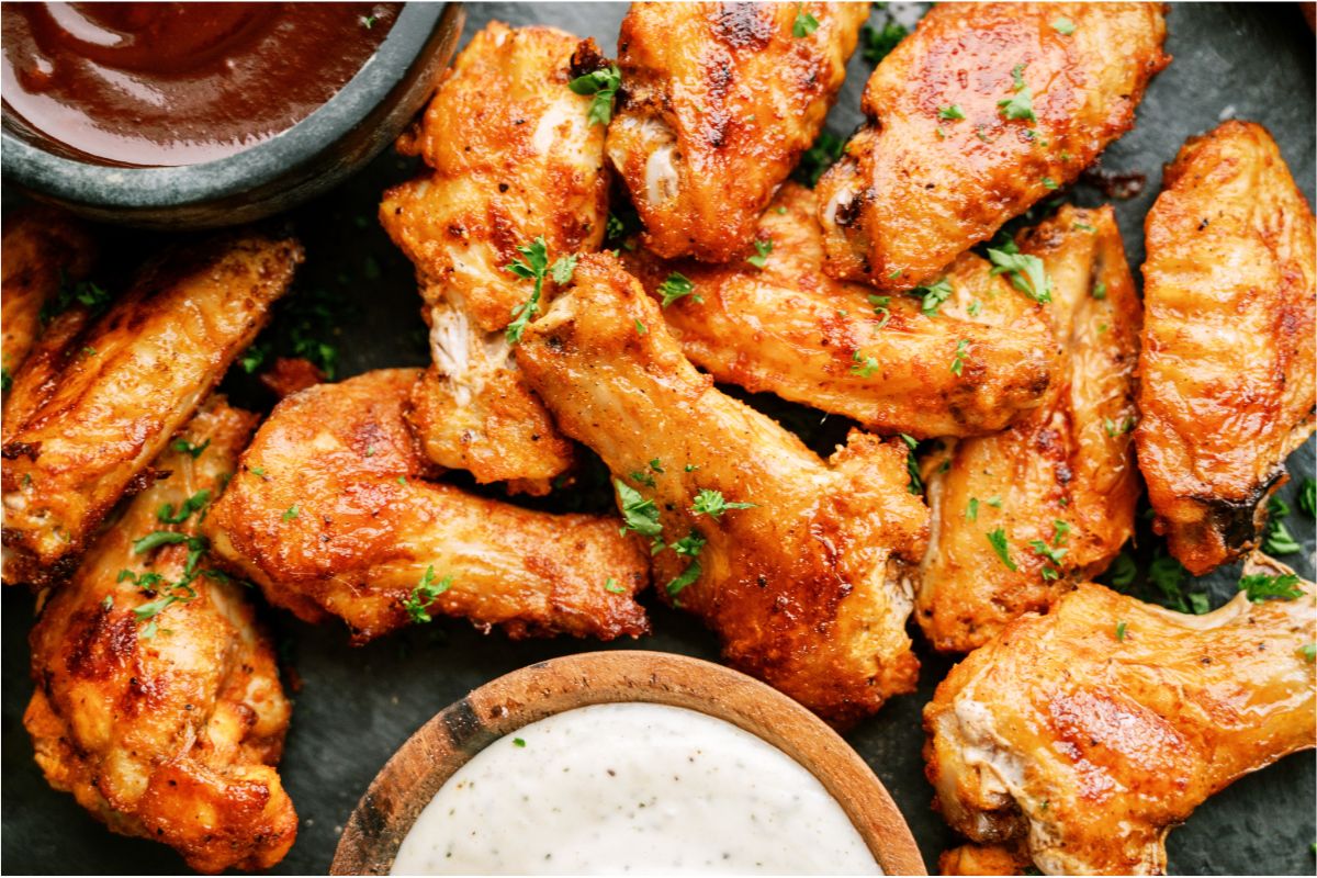 Crispy Baked Chicken Wings on a countertop with a side of ranch dip and bbq dip.