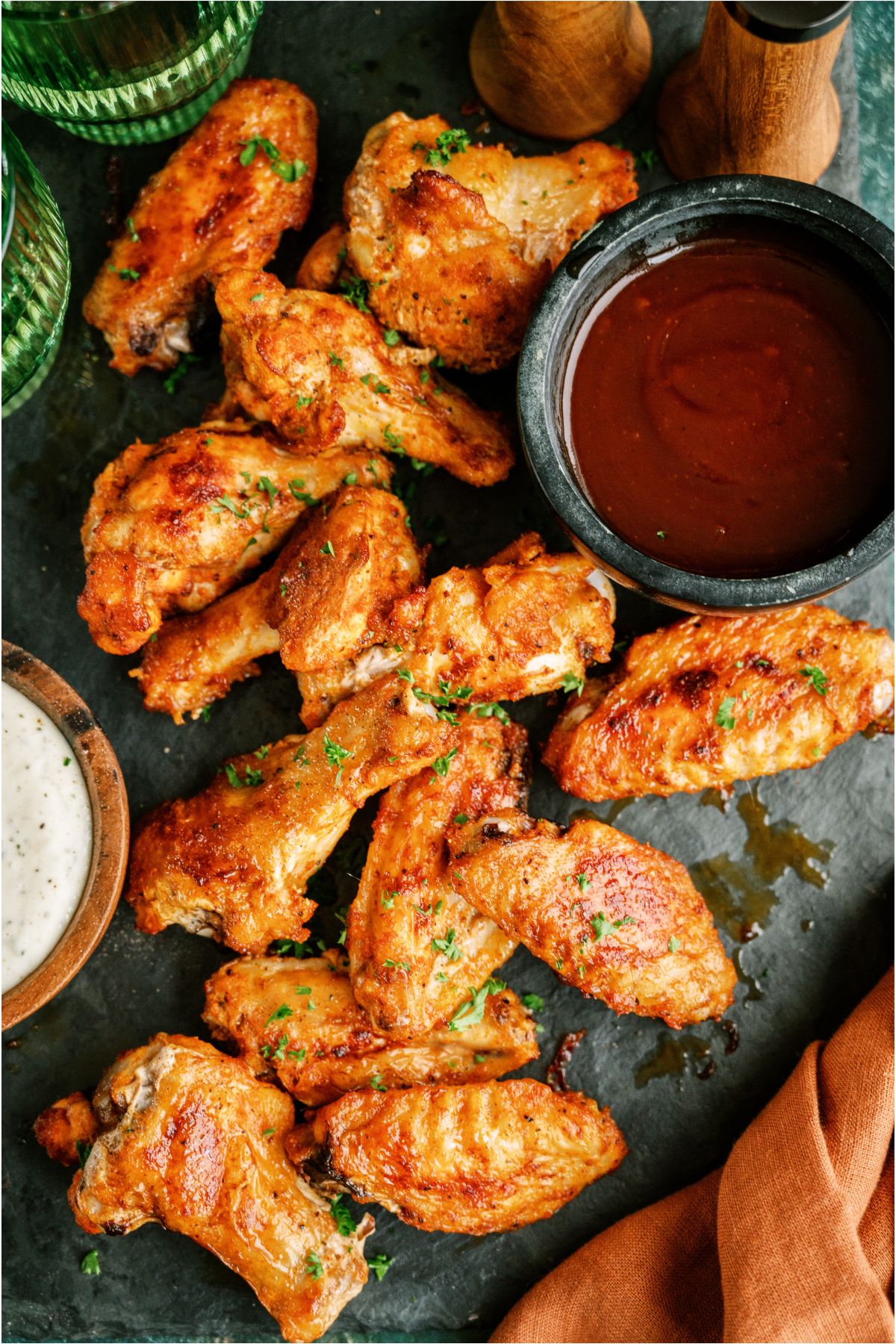 Top view of Crispy Baked Chicken Wings with a small bowl of BBQ sauce and a small bowl of ranch.