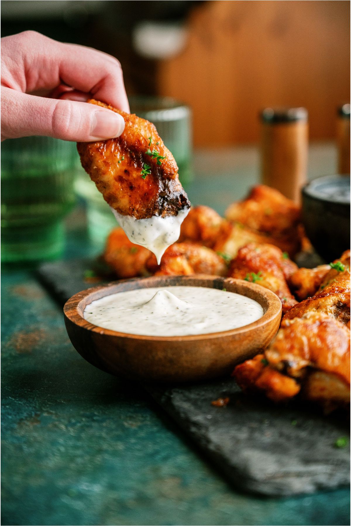 A hand dipping a Crispy Baked Chicken Wing in ranch.