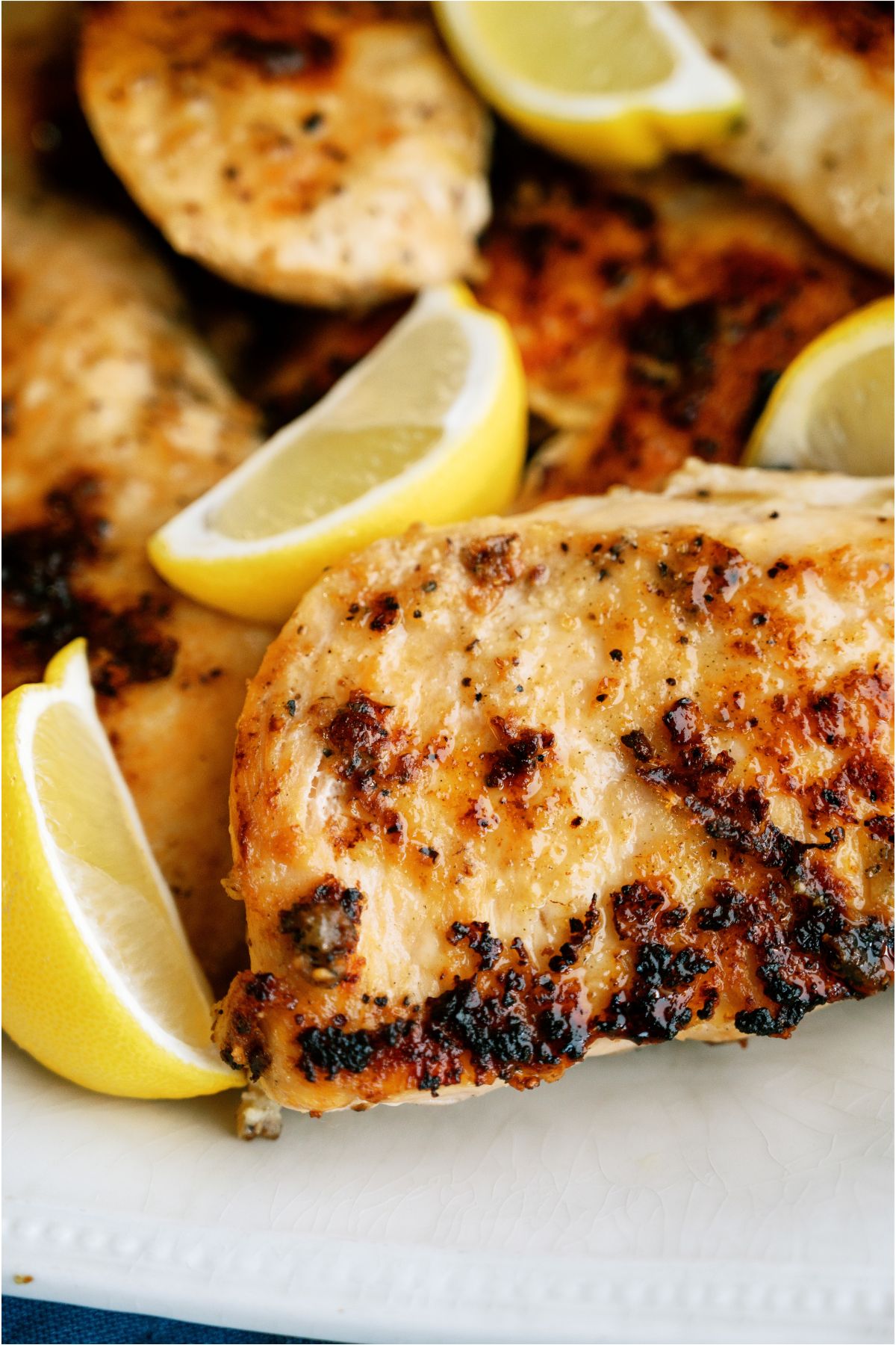 Close up view of a plate of Lemon Pepper Chicken with sliced fresh lemon wedges.