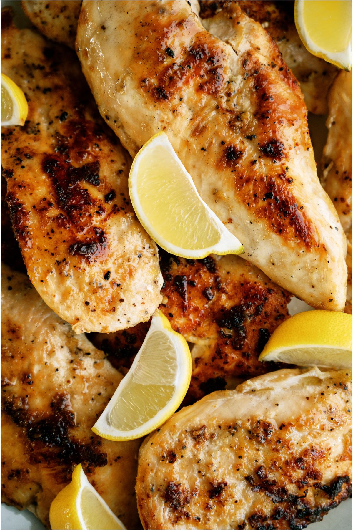 Top view of a plate of Lemon Pepper Chicken with sliced fresh lemon wedges.