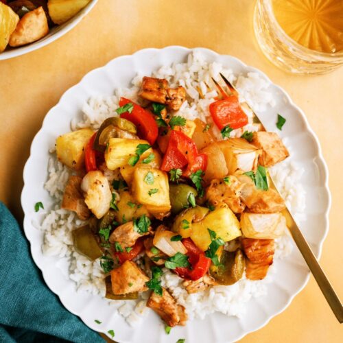 Top view of a plate of rice topped with Sheet Pan Hawaiian Chicken with a fork.