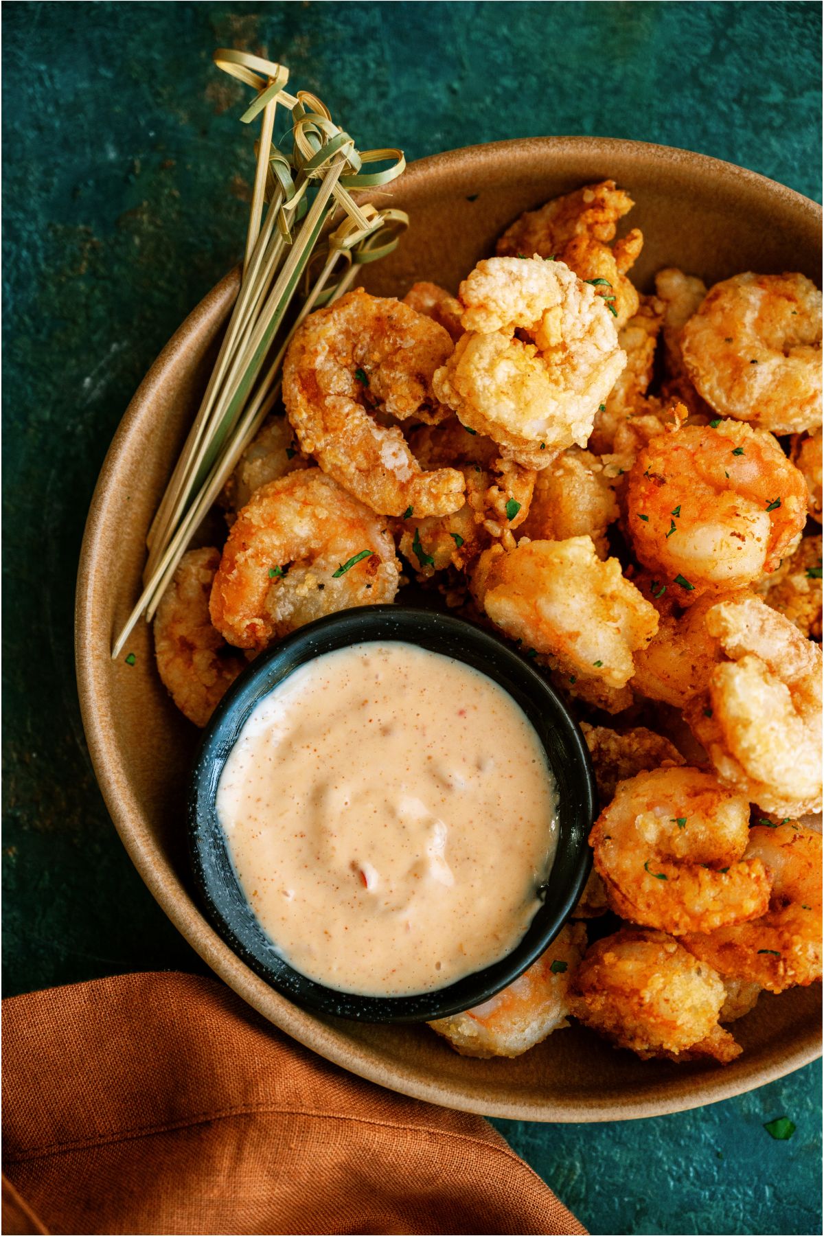 A bowl of Bang Bang Shrimp with a small cup of dipping sauce in the bowl and toothpicks.