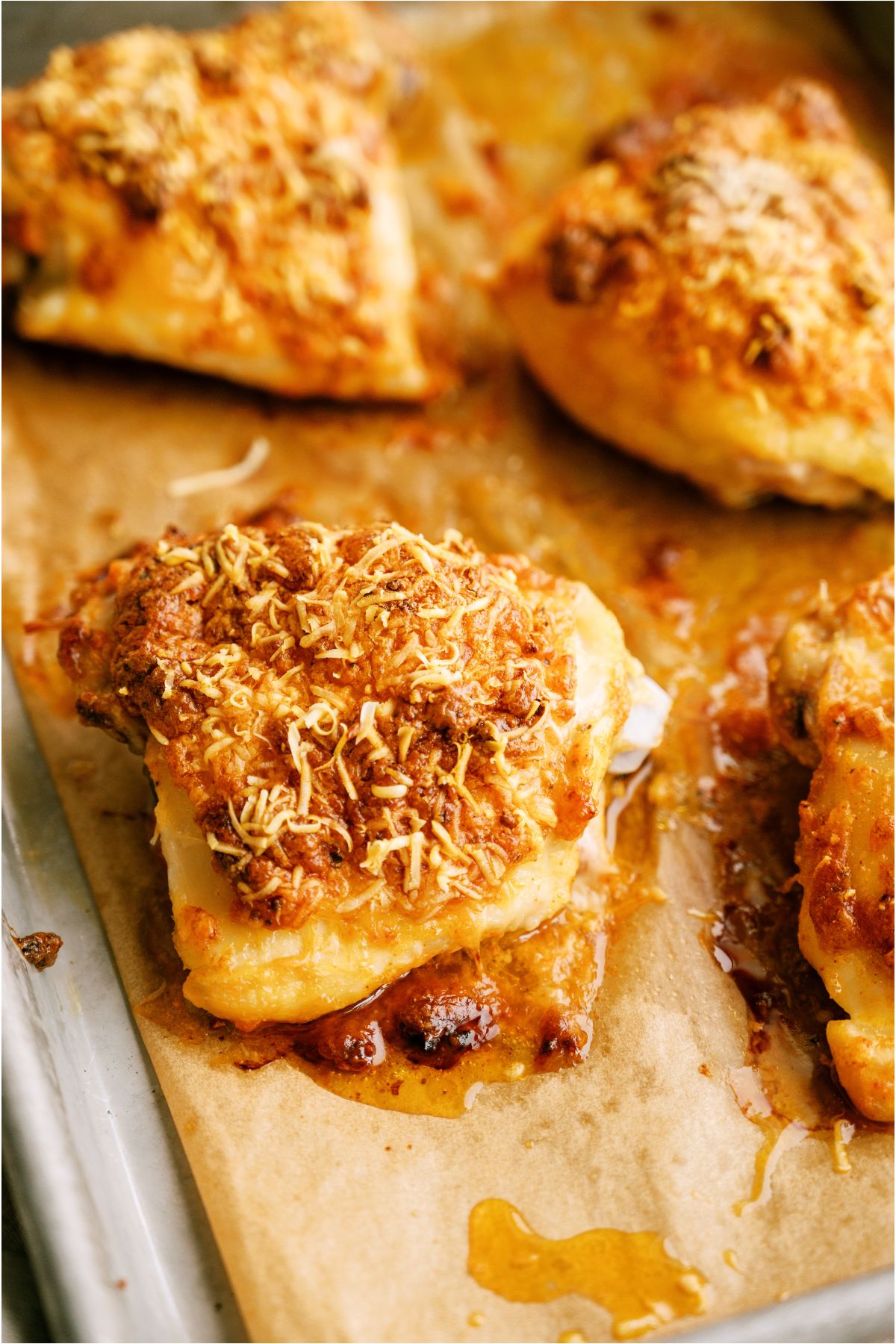 Several Creamy Garlic Parmesan Chicken Thighs on a parchment lined baking sheet.