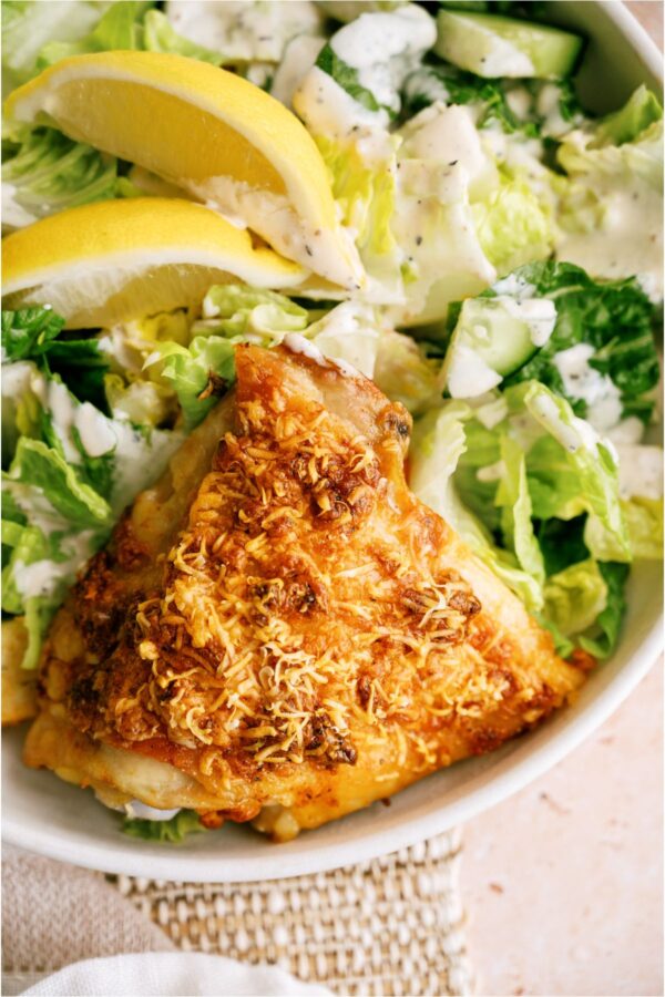 A piece of Garlic Parmesan Chicken on a plate with salad.