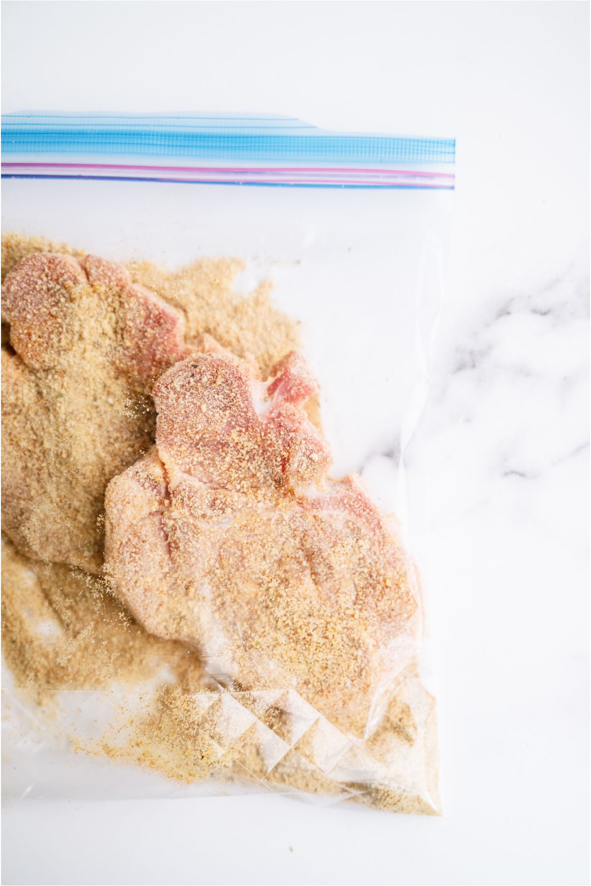 Pork chops in a ziploc bag with seasonings and bread crumbs.