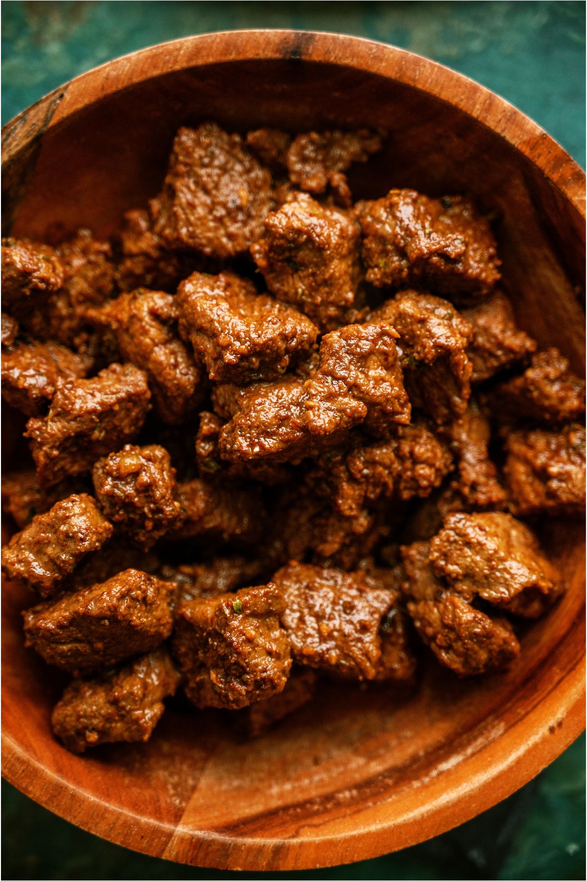 A wooden serving bowl filled with cooked Carne Asada meat.